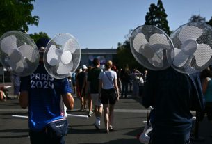 Des volontaires transportent des ventilateurs par une chaude journée d'été pendant les Jeux Olympiques de Paris 2024 devant l'Arena Paris Sud, le 29 juillet 2024